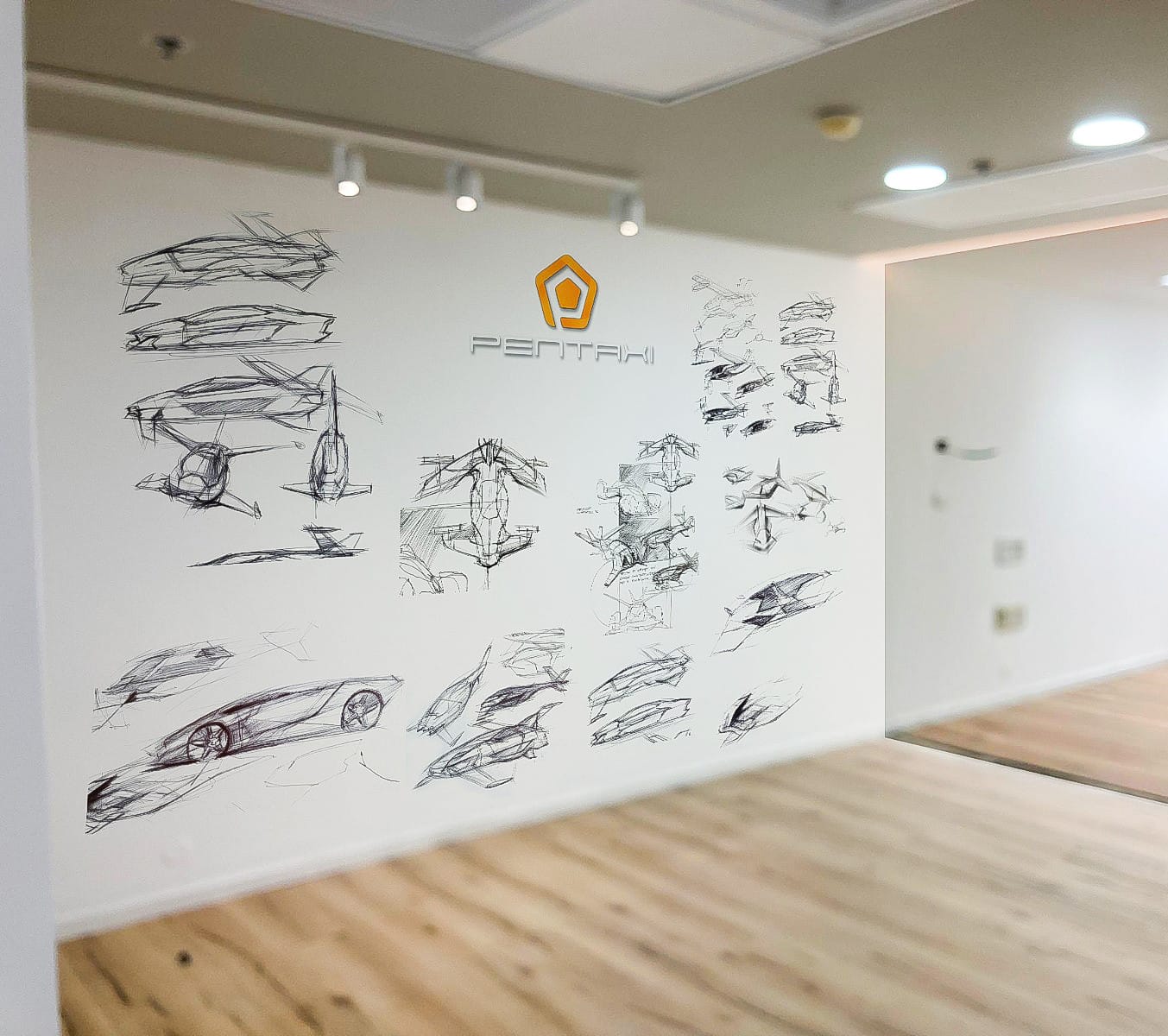 על קיר לבן במשרד מתנוסס הלוגו של Pentahi מעל מספר רישומים ידניים בשחור של מכוניות וכלי רכב עתידניים.